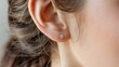 © kinara art design - Close up of a woman's ear with a diamond stud earring.