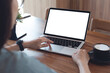 © tippapatt - Mockup laptop computer. Business woman using laptop with empty screen on wooden table in modern loft cafe. Back view
