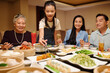 © DragonImages - Asian family eating rolls at dining table in the restaurant