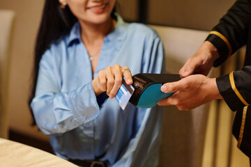 Young woman paying with credit card for her dinner in the restaurant