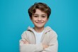 © Mitya - Happy kid with arms crossed smiling on blue background, isolated cheerful child portrait