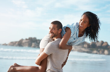 Wall Mural - Couple, happy and carry at beach for travel, summer and tropical holiday together in San Diego. Man, woman and walking on sand by ocean for adventure, love and relax on vacation with playful partner