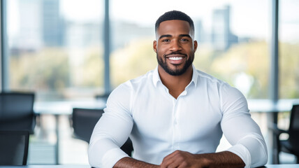 Confident Black man with a warm smile sits at a sleek conference table notebook open business casual attire office vibe bright window behind him 