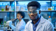 © Танюша Коновал - Portrait of young black African American scientist wearing protective glasses, standing in a laboratory interior. Chemist professional, medical experiment and research, copy space, specialist