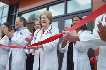 ribbon cutting ceremony at hospital entrance, doctors and nurses clapping, healthcare workers celebr
