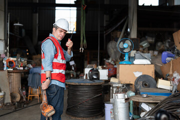 Wall Mural - Senior male construction worker using walkie-talkie and woking in warehouse of tower crane assembly factory.