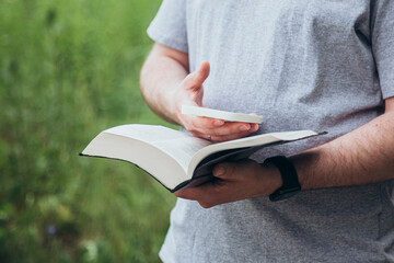 A man with a smart phone and a Bible in his hands outside.