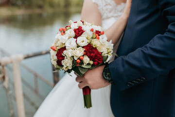 A bride and groom are holding a bouquet of flowers. The bride is wearing a white dress and the groom is wearing a blue suit