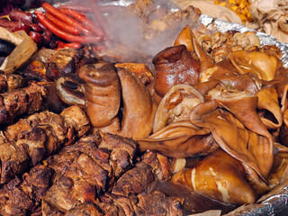 Hot street food made from fried pork in the form of kebabs, various sausages and smoked pork skin closeup.	