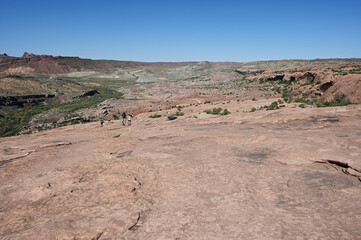 Wall Mural - Hikers on broad sandstone expanse of Delicate Arch Trail in Arches National Park near Moab, Utah on clear sunny summer morning.