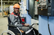 © pressmaster - Industrial worker in wheelchair smiling while operating machinery in factory setting, showing determination and competence. Wearing helmet and safety gear, focused on task