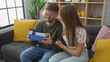© Krakenimages.com - Woman surprises man with gift in a cozy living room, sharing a joyful and intimate moment together.