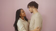 © Krakenimages.com - Affectionate man and woman embracing lovingly against a pink background, portraying a warm couple moment.