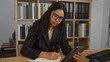 © Krakenimages.com - Woman writing notes on tablet at workplace with organized bookshelves in background