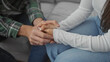 © Krakenimages.com - A man and woman sit closely on a sofa, holding hands intimately in a cozy living room, symbolizing love and togetherness.