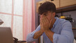 © Krakenimages.com - A young hispanic man looks stressed while sitting in an office room with his hands covering his face.