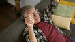 © Krakenimages.com - A cheerful senior man relaxing at home on a couch with bright pillows, embodying comfort and casual lifestyle.