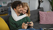 © Krakenimages.com - A happy couple of a man and a woman sit together playing a video game in the cozy living room of their apartment.