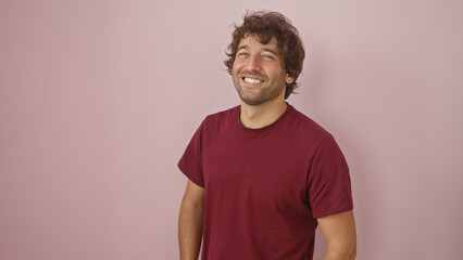 Poster - A cheerful young hispanic man with a beard smiling against a soft pink isolated background.