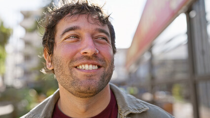 Sticker - Close-up of a smiling young hispanic man with a beard in an urban street setting.