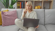 © Krakenimages.com - Blonde woman gesturing no while working on laptop in a modern living room.