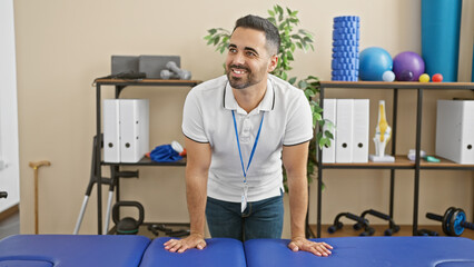 Canvas Print - A smiling hispanic man with a beard wearing a lanyard in a physical therapy clinic