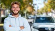 © Pinklife - A young man with a broad smile, wearing a gray hoodie, standing confidently outdoors in a residential area with a parked car in the background.