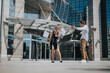 © qunica.com - Excited business colleagues joyfully tossing papers in celebration of success outside a modern office building in bright daylight.
