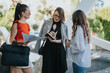 © qunica.com - Three professional businesswomen collaborating and reviewing documents in an outdoor, modern setting. Concept of teamwork, leadership, and business planning.