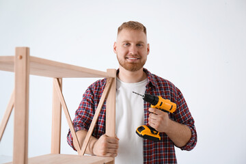 Poster - Man with electric screwdriver at home. Assembling furniture