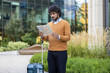 © Liubomir - Businessman stands outdoors holding map, preparing for city exploration. Urban setting with modern office background. Professional attire suggests business travel mood in vibrant city environment.