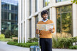 © Liubomir - Man with curly hair holds map standing beside suitcase in modern city. Urban traveler explores streets, highlighting adventure and exploration. Enjoyment and planning evident in outdoor environment.