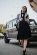 © qunica.com - Confident businesswoman in professional attire holding a notebook and pen while standing by a luxury car, showcasing success and determination.