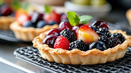 A beautifully crafted mixed berry tart featuring strawberries, blueberries, blackberries, and a fresh mint garnish, perfect for a sweet treat or dessert display.