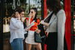 © qunica.com - Three young businesswomen having a meeting outdoors. They are discussing work, holding documents, and seem engaged in a professional conversation.