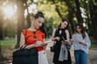© qunica.com - Young businesswomen working in a park. Focused on writing and discussing ideas. Professional collaboration and outdoor work environment.