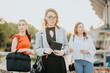 © qunica.com - Three businesswomen standing outdoors while holding documents and carrying bags. They are dressed in professional attire, displaying confidence and focus.