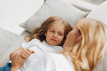 Wall Mural - Mother and daughter sharing a tender moment on the couch, gazing into each other's eyes with love and warmth