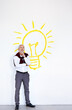 © peopleimages.com - Mature businessman, thinking and light bulb with idea for solution, brainstorming or planning on a wall background. Senior, male person or employee in wonder, contemplating or thought for decision