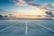 © Tee - Empty parking lot under a vibrant sunset sky with dramatic clouds and calm sea in the background, offering a serene and tranquil atmosphere.