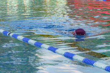 Poster - A competitive swimmer swims in a pool during training.