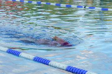 Poster - A competitive swimmer swims in a pool during training.