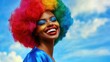 © zhou yan - Celebratory close-up of a joyful African American woman in vibrant clown wig and makeup at a pride parade, showcasing diversity and inclusion against a clear blue sky backdrop, ideal for social awaren