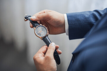 Wall Mural - A man is wearing a watch and holding it up to his face. The watch is black and gold