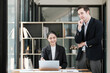 © Treerat - A man and a woman are standing in front of a desk with a laptop