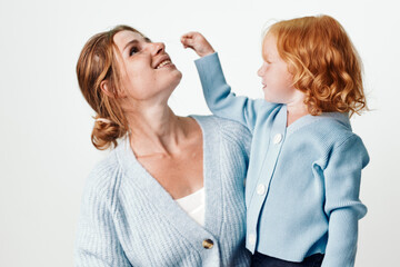 Wall Mural - Happy mother and daughter smiling together against white background in a joyful family moment