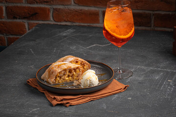 Wall Mural - Portion of German strudel with ice cream and an Aperol Spritz cocktail