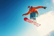 © Alexandra - Snowboarder is jumping high in the air, performing a grab trick with a bright blue sky in the background