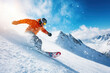 © Running opossum - Snowboarder wearing a helmet and orange jacket is snowboarding down on a snowy off-piste slope