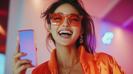 Wall Mural - Cheerful brunette Asian woman dance to favorite song moves to rhythm of music holds modern smartphone wears trendy orange sunglasses stylish jacket expresses happiness and joy models i : Generative AI